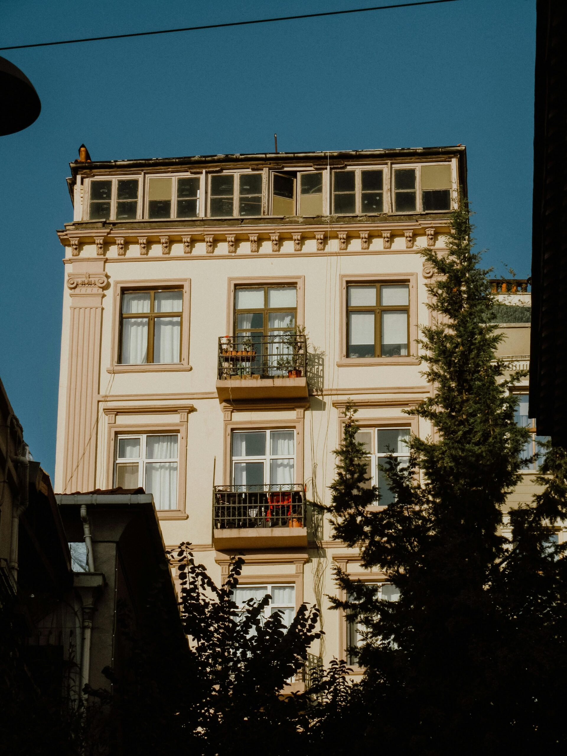 An impressive vintage apartment building with intricate design and glass windows under a clear blue sky.