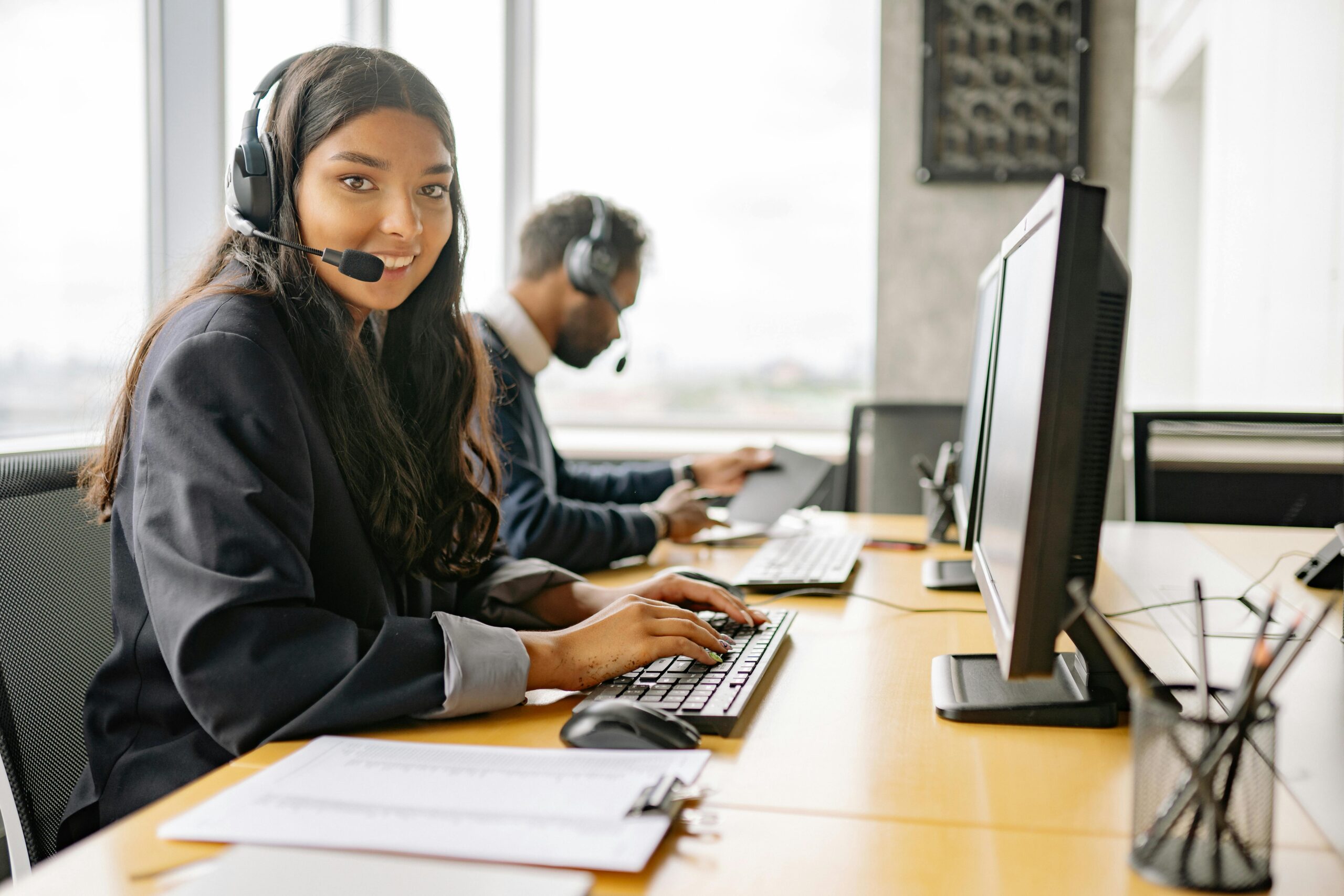 Smiling call center agents in an office providing customer support on computers.